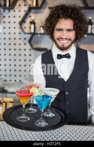 Barista tenendo il vassoio di cocktail e frullato in bar Foto Stock