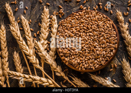 Spighe di grano e la tazza di chicchi di grano sul blu sullo sfondo di legno Foto Stock