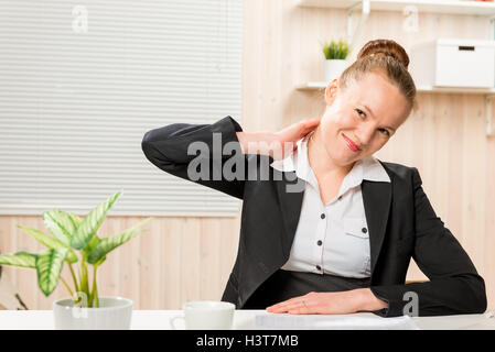 La donna in un business suit strofinando il suo collo, che è mal di lavorare a un computer Foto Stock
