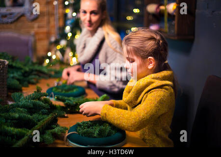 Madre e figlia di decorazione ghirlanda di conifere. Celebrazione della Messa di Natale concept Foto Stock