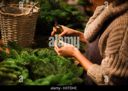 Fioraio donna decorazione ghirlanda di conifere. Foto Stock