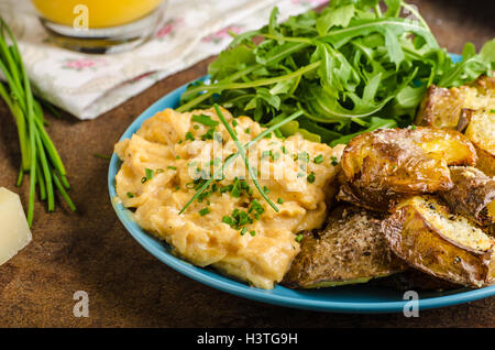 Croccante di purè di patate, uova strapazzate e un po' di insalata, succo di frutta e torta per la deliziosa prima colazione Foto Stock