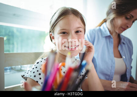 Figlia sorridente seduto accanto a sua madre Foto Stock