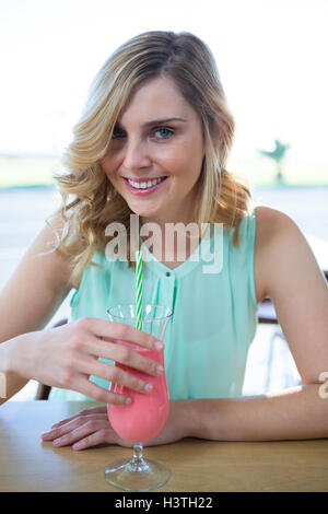 Ritratto di donna sorridente avente un drink frullato Foto Stock