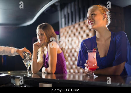 Cameriere versando un cocktail nella donna di vetro al bancone bar Foto Stock