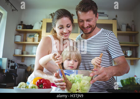 I genitori a guardare la loro figlia miscelare l'insalata Foto Stock