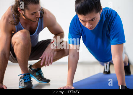 Istruttore di Fitness fitness aiuta l uomo con push-up Foto Stock