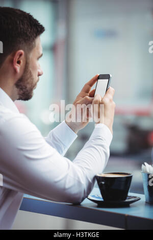 Uomo che utilizza il cellulare mentre un caffè Foto Stock