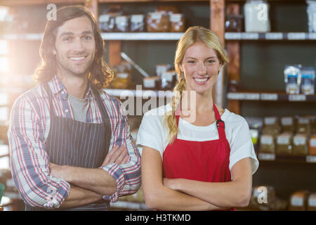 Il personale sorridente in piedi con le braccia incrociate nel supermercato Foto Stock