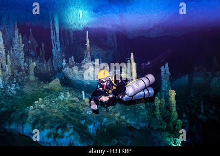 Tuffati in una grotta di cenote a Tulum, Messico, circondata da acque turchesi, formazioni calcaree e raggi di luce, catturando la bellezza dell'Explore subacqueo Foto Stock