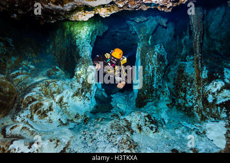 Tuffati in una grotta di cenote a Tulum, Messico, circondata da acque turchesi, formazioni calcaree e raggi di luce, catturando la bellezza dell'Explore subacqueo Foto Stock