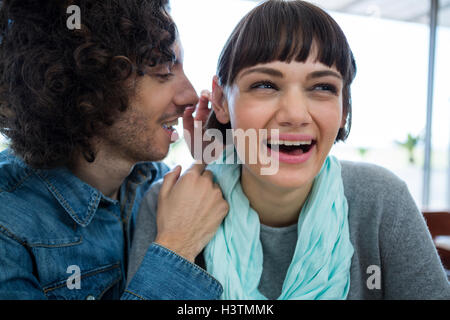 L'uomo whispering nella donna s orecchio Foto Stock