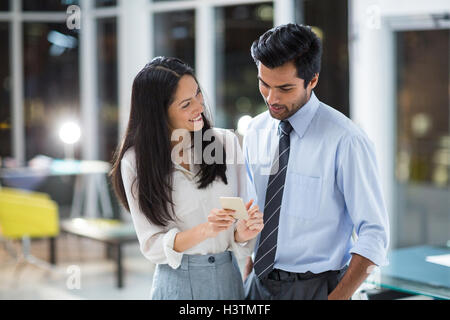 Imprenditrice che mostra il telefono cellulare a un collega Foto Stock