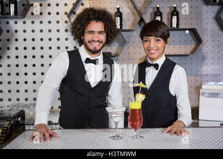 Cameriera e cameriere in piedi in banco bar con cocktail Foto Stock