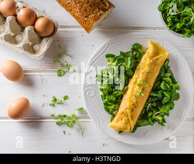 Vero frittata francese con insalata, piacevole e soffice e tavolo in legno bianco Foto Stock