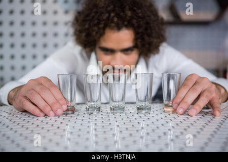 Barista immissione bicchierini sul bancone bar Foto Stock