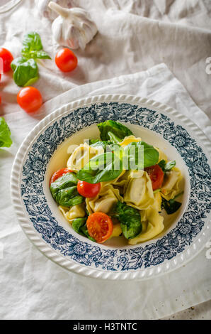 Tortellini con ripieno di carne arrosto con pomodoro e basilico, olio d'oliva Foto Stock