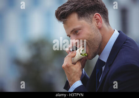 Imprenditore bello mangiare spuntini Foto Stock