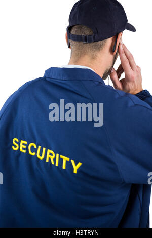 Vista posteriore del security officer ascolto di auricolare Foto Stock