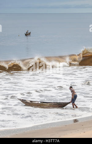 Pescatore con una piroga sulla spiaggia, Kribi, regione sud, Camerun Foto Stock