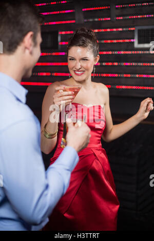 Coppia sorridente tenendo un bicchiere di birra e un cocktail mentre balli Foto Stock