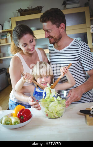 I genitori a guardare la loro figlia miscelare l'insalata Foto Stock