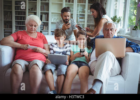 Multi-generazione famiglia utilizzando computer portatili, telefoni cellulari e tablet digitale Foto Stock