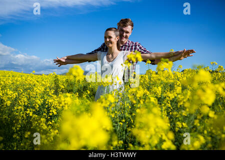 Coppia romantica in piedi con le braccia aperte in campo di senape Foto Stock