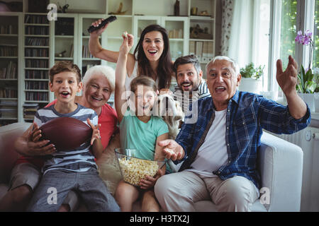 Felice multi-generazione famiglia guardare la partita di calcio in televisione nel soggiorno Foto Stock