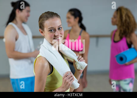 Ritratto di donna azienda trainer asciugamano con lezione di fitness in background Foto Stock