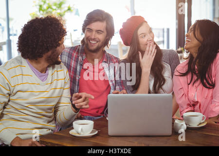 Ridere gli amici sorseggiando un caffè con laptop Foto Stock