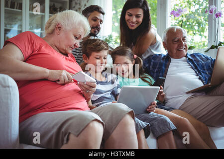 Felice multi-generazione famiglia utilizzando computer portatili, telefoni cellulari e tablet digitale Foto Stock
