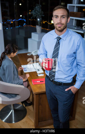 Business executive in piedi con una tazza di caffè Foto Stock