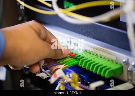 Il tecnico collegando il cavo patch in un rack server Foto Stock