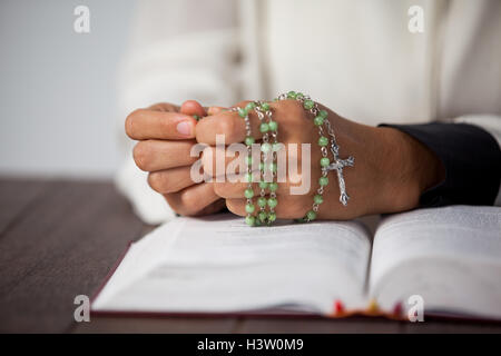 Pregando le mani di una donna con il rosario sulla bibbia Foto Stock