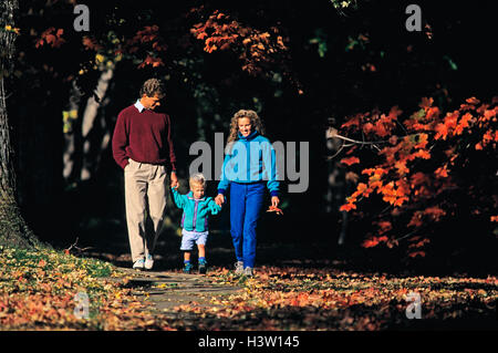 Genitori e figlio camminando sul marciapiede in autunno Foto Stock