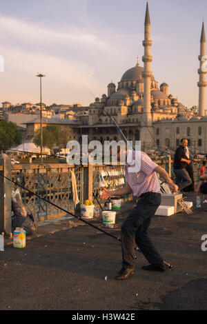 Fisherman cercando di costante il pesce che egli aveva appena catturato (vicino al suo piede sinistro), a Istanbul (Turchia) Foto Stock