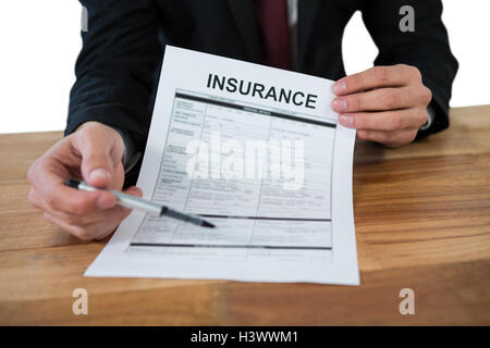 La sezione centrale del proprietario seduto alla scrivania con contratto di assicurazione Foto Stock