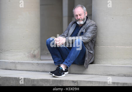 Stuttgart, Germania. Xii oct, 2016. Attore Liam Cunningham, che è noto come knight 'Ser Davos" dalla serie 'Gioco di troni', sorge tra i pilastri di Stoccarda (Germania), 12 ottobre 2016. A Stoccarda si è incontrato con il rifugiato siriano boy Hussam Al-Heraki. L'attore aveva avuto modo di conoscere il ragazzo quando ha visitato un campo di rifugiati in Giordania con l'organizzazione di aiuti World Vision. Foto: MARIJAN MURAT/dpa/Alamy Live News Foto Stock