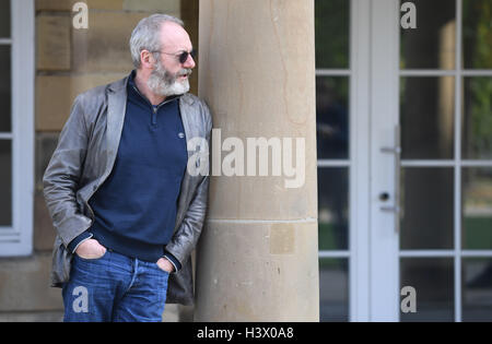 Stuttgart, Germania. Xii oct, 2016. Attore Liam Cunningham, che è noto come knight 'Ser Davos" dalla serie 'Gioco di troni', sorge tra i pilastri di Stoccarda (Germania), 12 ottobre 2016. A Stoccarda si è incontrato con il rifugiato siriano boy Hussam Al-Heraki. L'attore aveva avuto modo di conoscere il ragazzo quando ha visitato un campo di rifugiati in Giordania con l'organizzazione di aiuti World Vision. Foto: MARIJAN MURAT/dpa/Alamy Live News Foto Stock