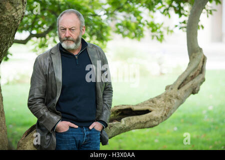 Stuttgart, Germania. Xii oct, 2016. Attore Liam Cunningham, che è noto come knight 'Ser Davos" dalla serie 'Gioco di troni', sorge tra i pilastri di Stoccarda (Germania), 12 ottobre 2016. A Stoccarda si è incontrato con il rifugiato siriano boy Hussam Al-Heraki. L'attore aveva avuto modo di conoscere il ragazzo quando ha visitato un campo di rifugiati in Giordania con l'organizzazione di aiuti World Vision. Foto: MARIJAN MURAT/dpa/Alamy Live News Foto Stock