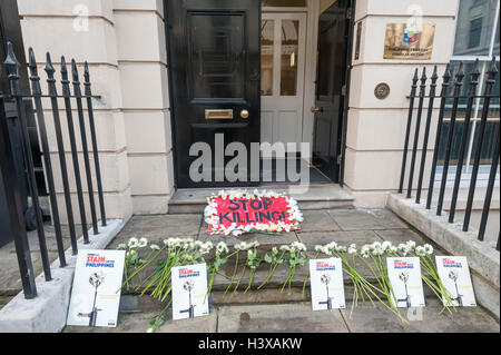 Londra, Regno Unito. Xiii oct, 2016. Manifestanti laici fiori bianchi e manifesti sui passi dell'Ambasciata delle Filippine. Essi esigono per Presidente Rodrigo Duterte fine i suoi ripetuti inviti per le forze di polizia e di pubblica per uccidere coloro che utilizzano e trattare la droga e ritirare la sua promessa non vi saranno azioni penali per queste esecuzioni extragiudiziali. Poiché Duterte arrivò al potere alla fine di giugno vi sono state oltre 3500 tali uccisioni illegali sulle strade. Credito: Peter Marshall / Alamy Live News Foto Stock