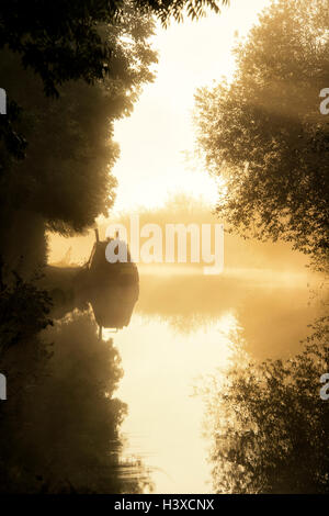 Narrowboat in una nebbiosa oxford canal nelle prime ore del mattino. Oxfordshire, Inghilterra. Silhouette Foto Stock