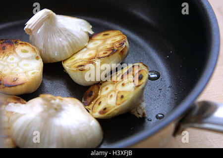 Padella, aglio Allium sativum, noduli, metà, arrosto, still life, aglio noduli, diviso, metà, chiodi di garofano di aglio, porri tipo, spice, noduli, sear tostate, padella, close up Foto Stock