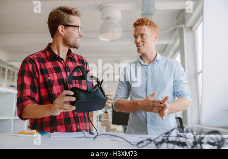 Colpo di due giovani sviluppatori discutendo sulla nuova realtà virtuale occhiali. Colleghi di lavoro lavorando sullo sviluppo di nuovi occhiali VR Foto Stock