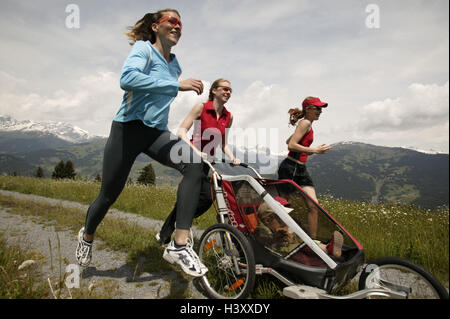 Vicolo del paese, donne, ragazze, sportily, jog, spingere pareggiatore baby, giovani amici, filiale, neonati, carrozzine, sport, sportivi, jogging, in funzione, funzionante, la perseveranza, la perseveranza sport, stamina formazione, formazione, allenamento fitness abbigliamento sportivo Foto Stock