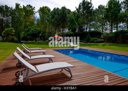 Sedie a sdraio accanto alla piscina all'aperto Foto Stock