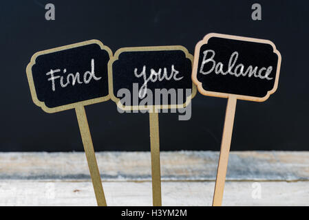 Messaggio motivazionale di trovare il tuo equilibrio scritto con gesso su legno lavagna mini etichette, lavagna sfocati e tavola di legno in background Foto Stock