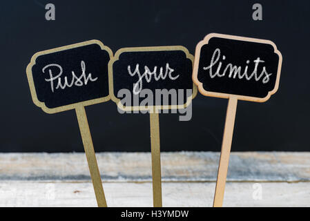 Messaggio motivazionale spingere i tuoi limiti scritto con un gessetto su legno mini etichette di Blackboard Foto Stock