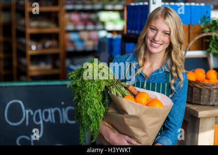 Ritratto di donna sorridente tenendo un sacco di negozi di generi alimentari nella sezione biologica Foto Stock